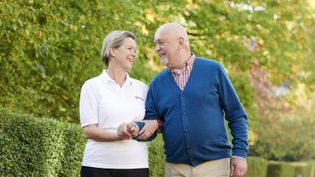 Mitarbeiterin begleitet Senior in den Friedhof