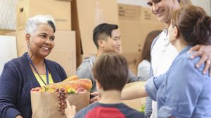 Es wird dargestellt, wie die Tafel Essensspenden an Bedürftige überreicht.