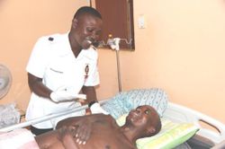 A care worker assists Nhlanhla in bed.