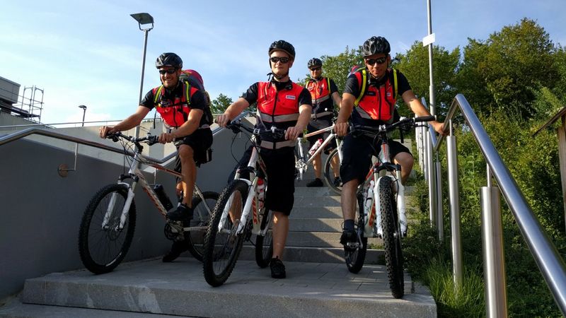 Vier Männer in Signalwesten auf Fahrrädern auf einer Betontreppe.