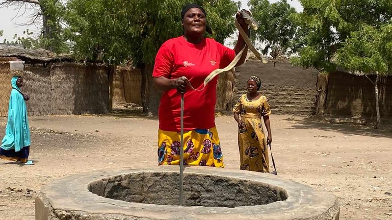 Eine Frau an einem Wasserbrunnen.
