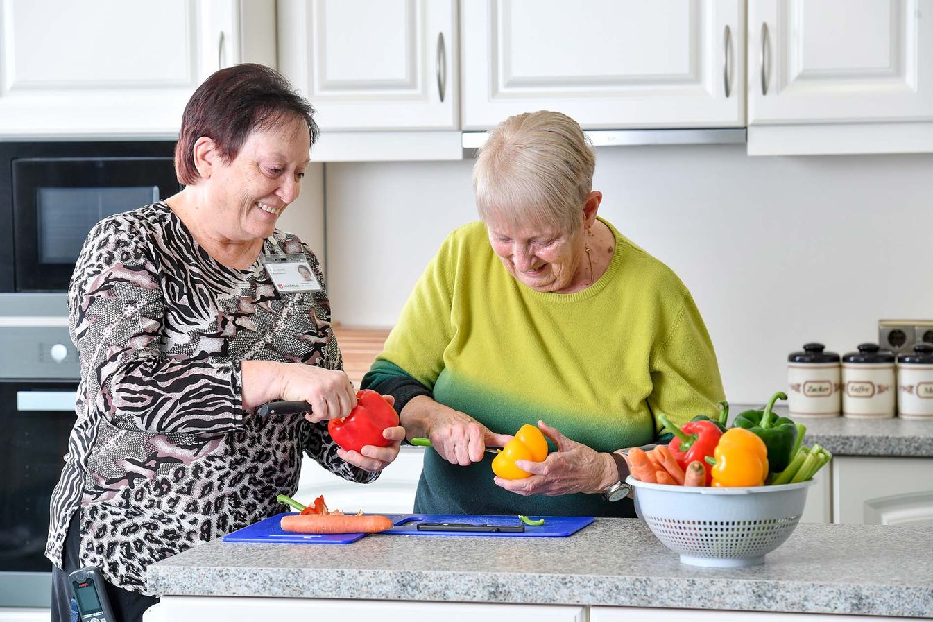 Pflegerin und Bewohnerin kochen gemeinsam 