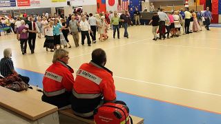 Zwei Malteser Sanitäter bei einer Veranstaltung in einer Turnhall.