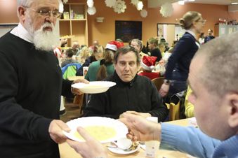 Ein Mann gibt einem Gast einen Teller mit warmem Essen. Foto: Hannemann/Malteser