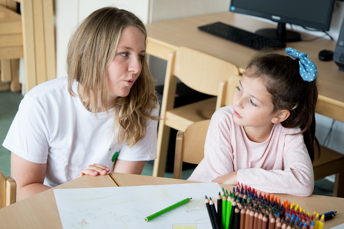 Kind und Frau sitzen am Tisch und malen