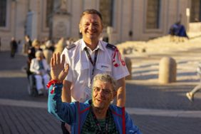 Ein Mann begleitet einen Menschen mit Behinderung im Rollstuhl. Foto: Malteser
