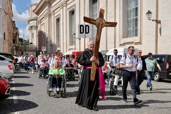 Eine Menschengruppe geht hinter dem Kreuz. Foto: Jochmann