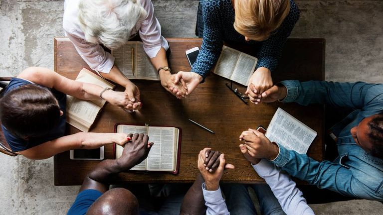  Ein älterer Mann sitzt im Schneidersitz mit geschlossenen Augen und Kopfhörern auf dem Fußboden eines Wohnzimmers.