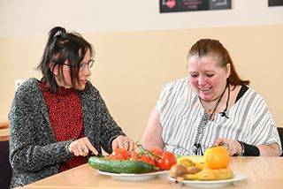 Pflegerin und Bewohnerin kochen zusammen 