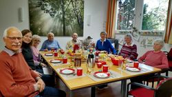 Ältere und jüngere Menschen sitzen um einen österlich gedeckten Tisch