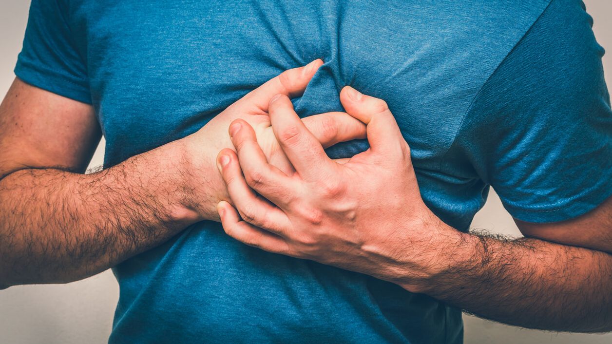 Mann im blauem T-Shirt fasst sich mit beiden Händen krampfhaft ans Herz