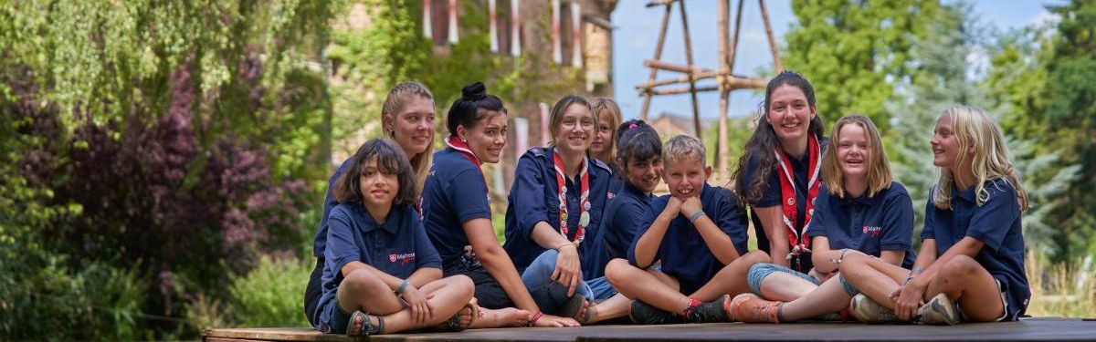 Eine Gruppe Kinder mit blauen T-Shirts vor einer Burg 