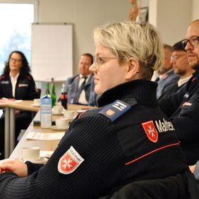 Frau und weitere Personen in Besprechungsraum