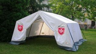 Bild vom einem aufgebauten SG50 mit zwei Malteser Wappen auf einer Wiese.