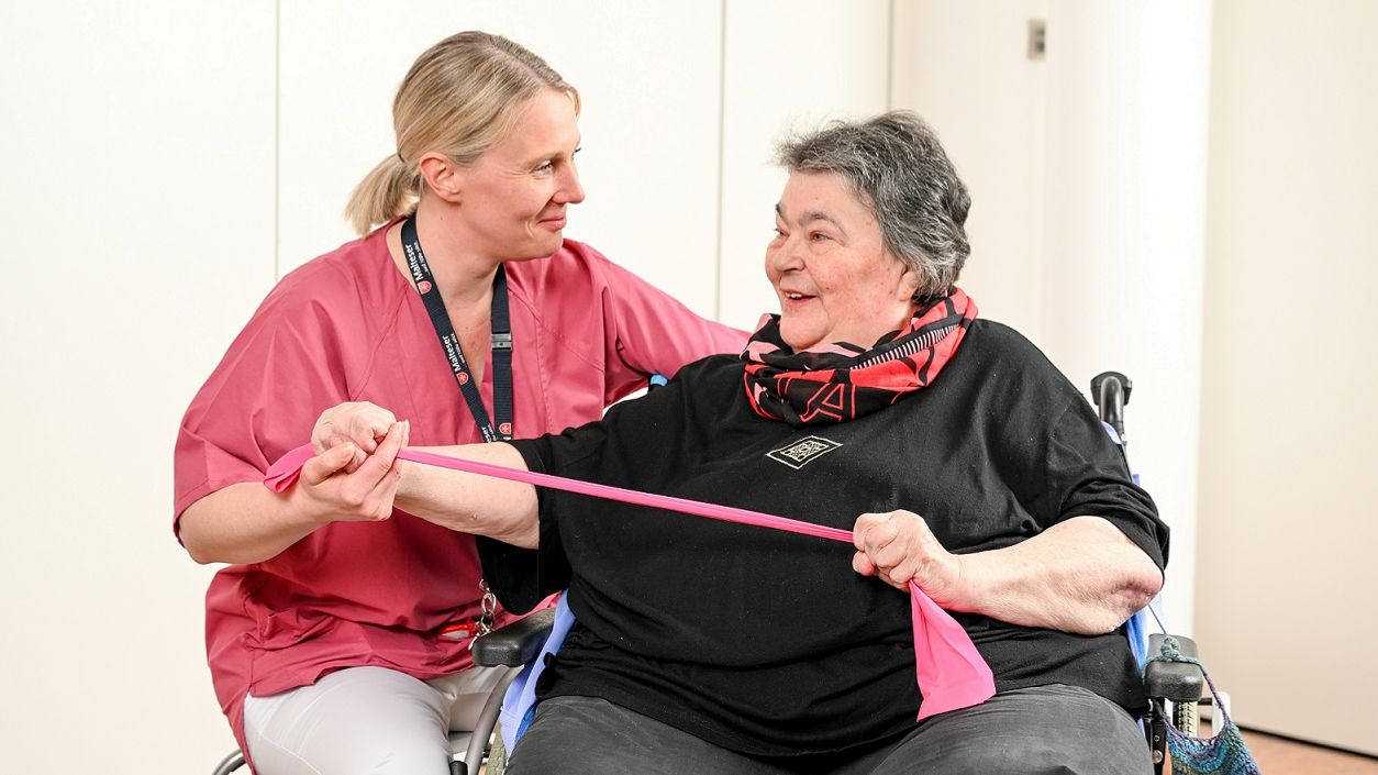 Pflegerin und eine Patientin mit einer Übung mit einem Terraband