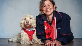Eine Frau und ein Hund, beide mit Malteser Halstuch schauen gemeinsam in die Kamera.
