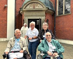 Personen stehend und sitzend, Kleidung, Rollstühle