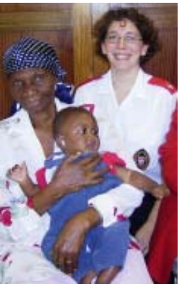 A woman holds a baby beside a care worker.