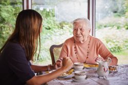 Eine Malteserin beim Kaffetrinken und Sprechen mit einer Seniorin.