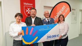 Zwei Frauen und zwei Männer halten einen großen Spendenscheck in der Hand.