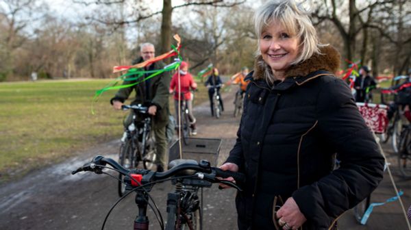 Eine lächelnde ältere Frau mit Fahrrad auf einer Demo.