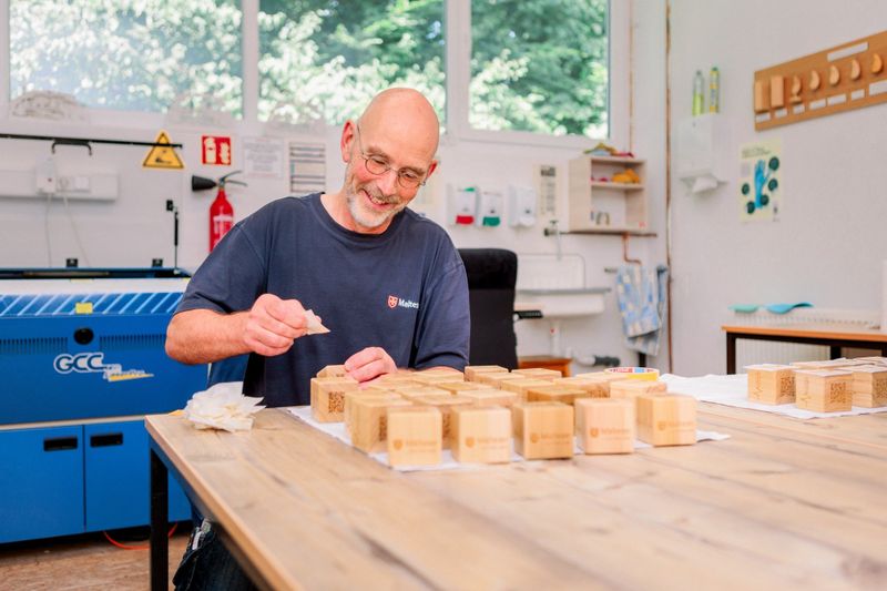 Ein lächelnder Mann stellt Werkstücke in einer Tischlerei her.