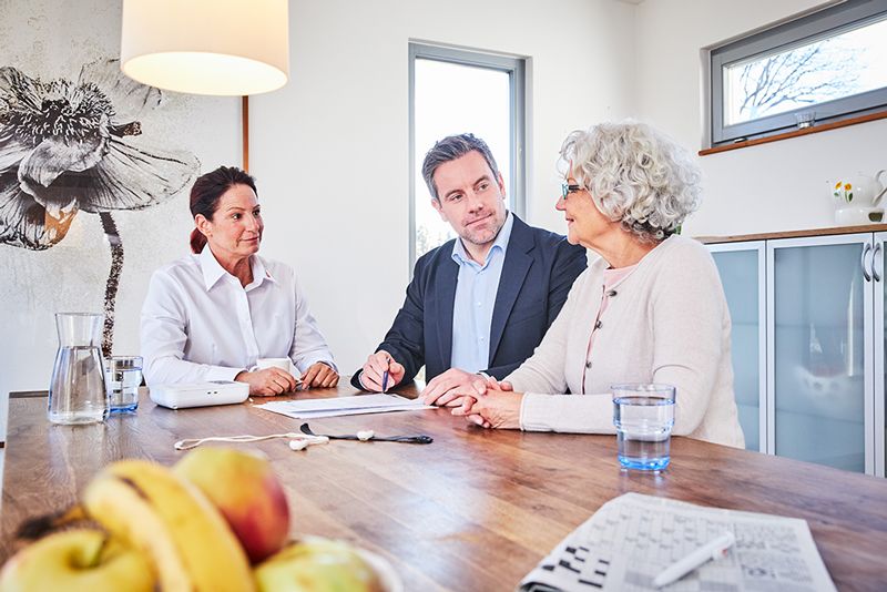 Demenz-Assistance: Beratungssituation am Tisch mit drei Menschen