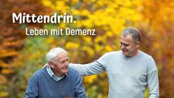 Ein jüngerer Mann legt einem älteren Mann den Arm um die Schulter.