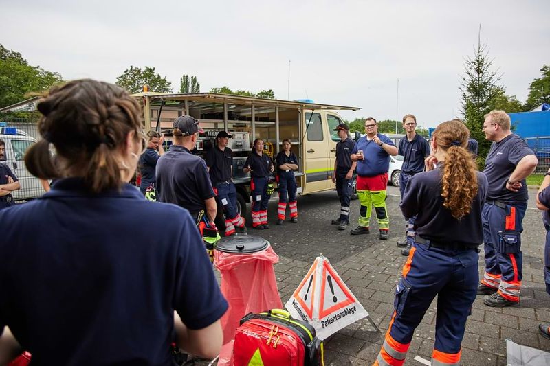 Eine Gruppe von Rettungskräften steht vor ihrem Fahrzeug zusammen und bespricht sich.