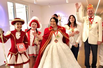 Karnevalsgruppe in festlichen rot-weißen Kostümen mit Prinzessin in weißem Kleid in der Mitte. 