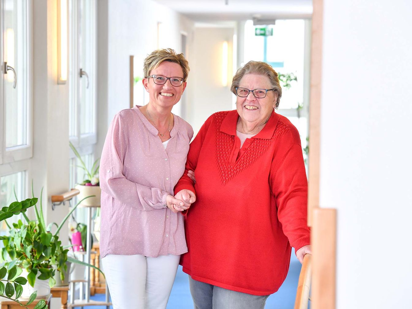 Pflegerin begleitet Bewohnerin durch den Flur