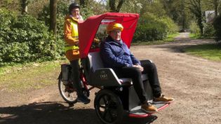 Eine Helferin der Lohner Malteser fährt einen älteren Herren in einer Rikscha im Hopener Wald.