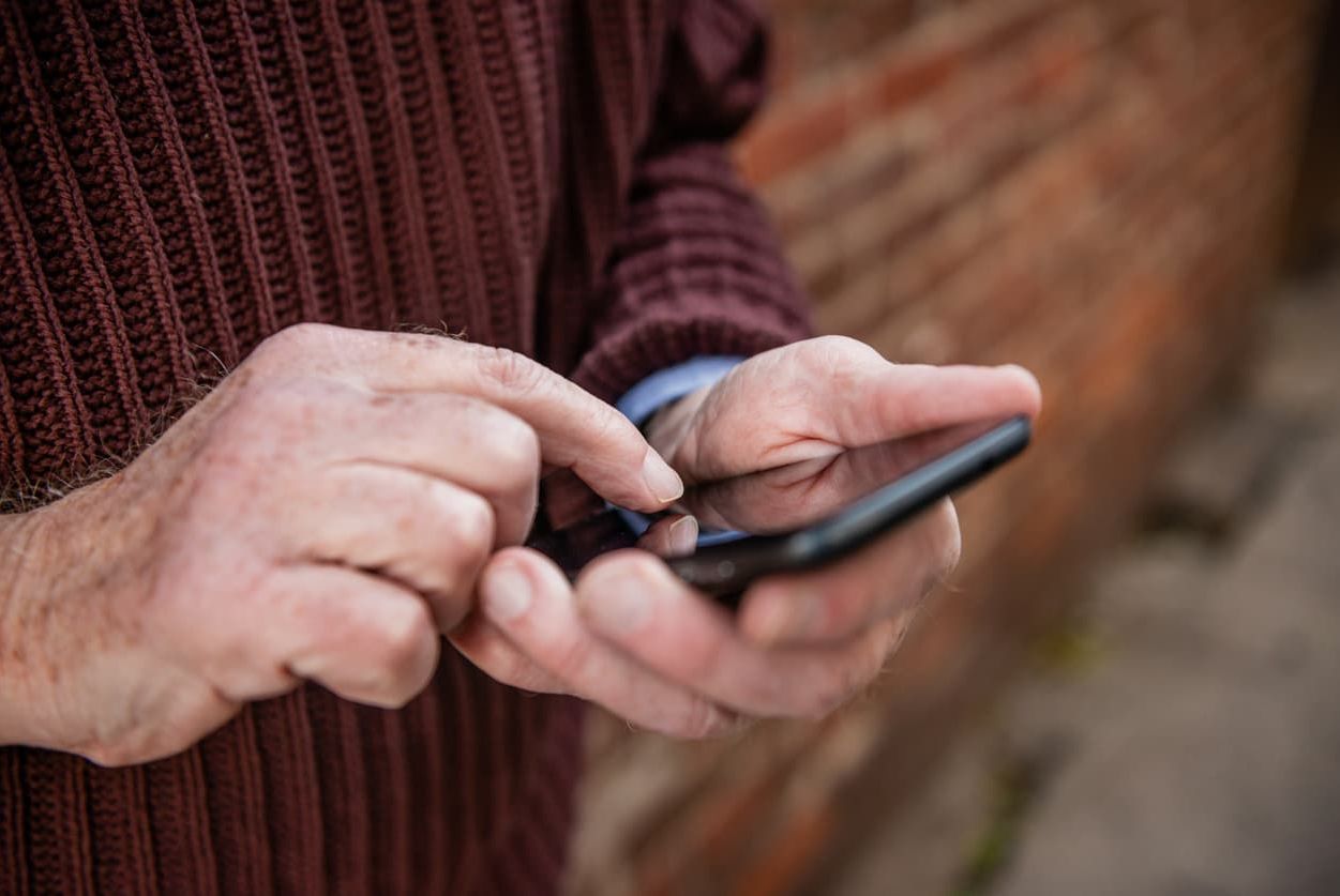 Hände halten und steuern Handy.