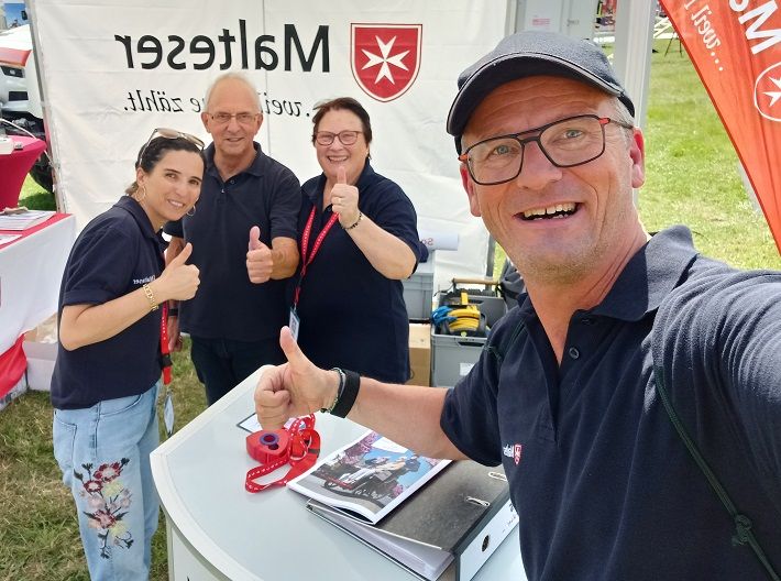 Vier Malteser machen ein Selfie und lachen in die Kamera