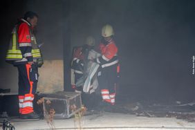 Die Verletzten werden von Rettungskräften aus der verrauchten Halle getragen 