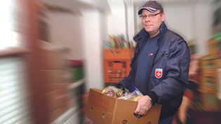 Ein Malteser-Helfer trägt einen Karton mit Lebensmitteln.