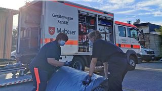 Malteser Mitarbeiter im Katastrophenschutz packen zusammen.