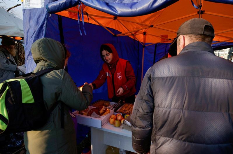 Eine Frau gibt Lebensmittel an Geflüchtete aus.