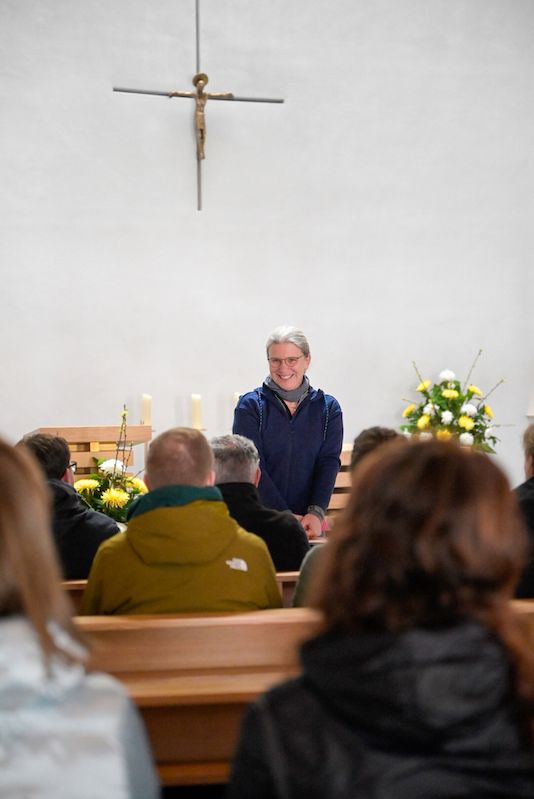 Dörte Schrömges steht vor einer Gruppe sitzender Menschen vorne in einer Kirche