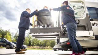 Zwei Mitarbeitende des Malteser Fahrdienstes helfen einer Person im Rollstuhl.