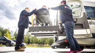 Zwei Mitarbeiter der Malteser befördern einen Rollstuhlfahrer zuverlässig.
