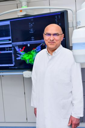 Mann im Arztkittel vor einem Monitor.