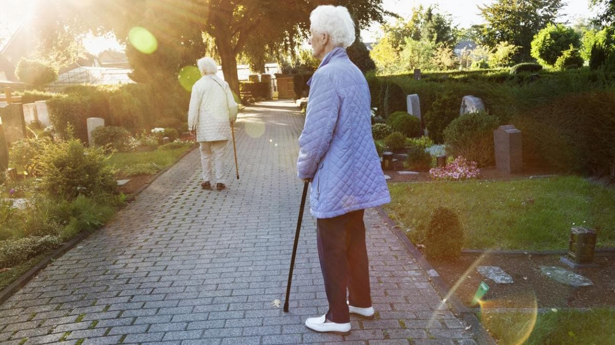 Zwei ältere Damen, die einen Friedhof besuchen.