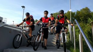 Vier Männer in Signalwesten auf Fahrrädern auf einer Betontreppe.