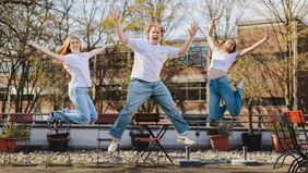 Drei junge Menschen bei einem Luftsprung.