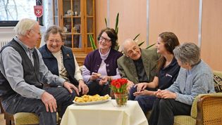 Mehrere ältere Menschen sitzen an einem Tisch.