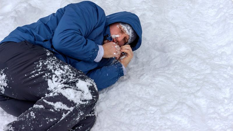 Mann in blauer Jacke liegt im Schnee