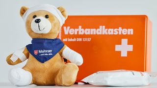 Erste Hilfe Verbandskasten mit Teddy, der verbunden und gepflastert ist