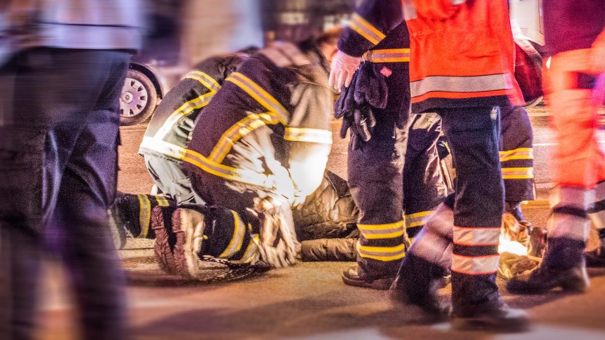 Rettungskräfte versorgen ein Unfallopfer auf einer nächtlichen Straße