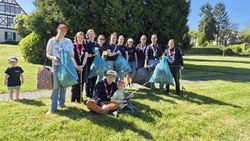 Gruppenfoto mit insgesamt 13 Kindern, Jugendlichen und ehrenamtlichen Gruppenleitungen, die 5 Müllsäcke hochhalten, die sie bei der Clean-Up Aktion gesammelt haben.